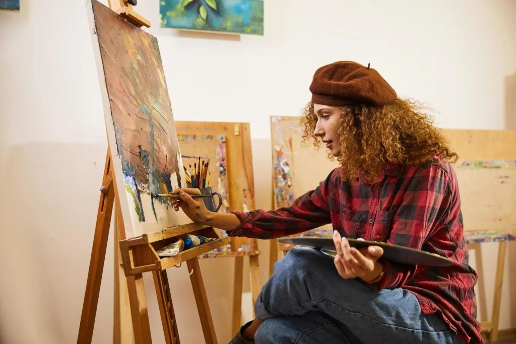 artist painting in her studio free photo